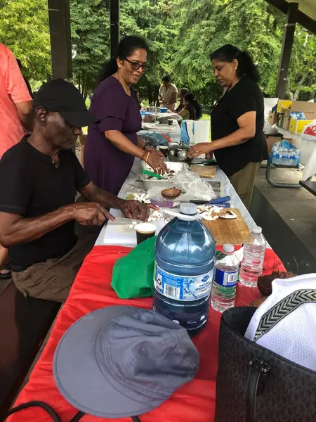People preparing food at a picnic table outdoors