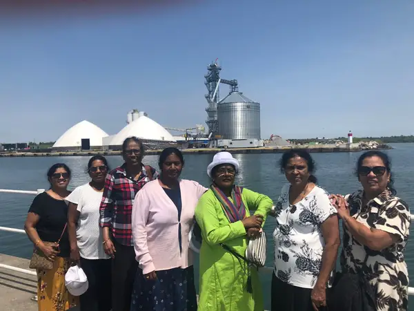 Group standing by the water with industrial silos behind them