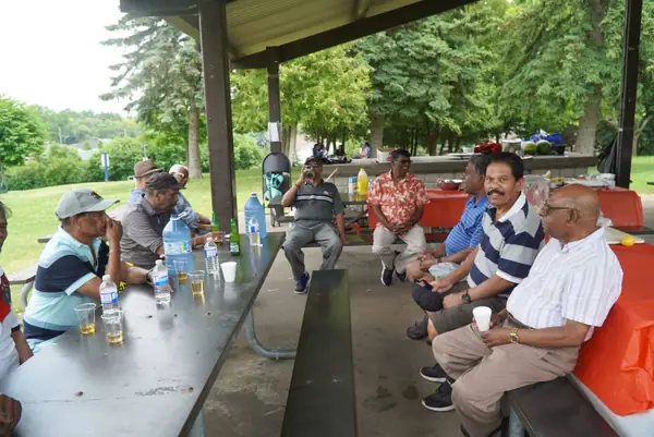 People seated at picnic tables under a pavilion