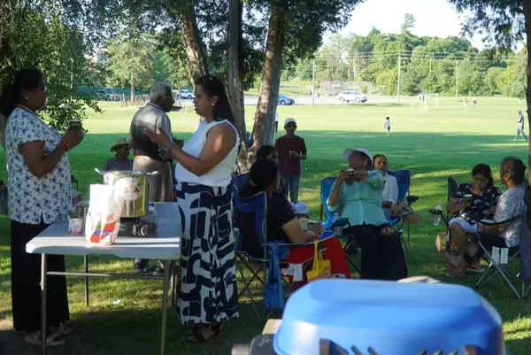 People gathered around a table on a sunny park lawn