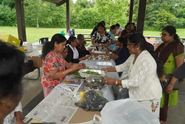 People preparing food at tables under a pavilion