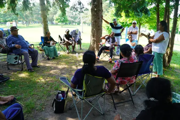 People seated in lawn chairs in a wooded park
