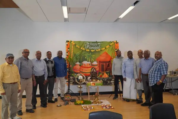 Group of men posing beside a decorated backdrop indoors