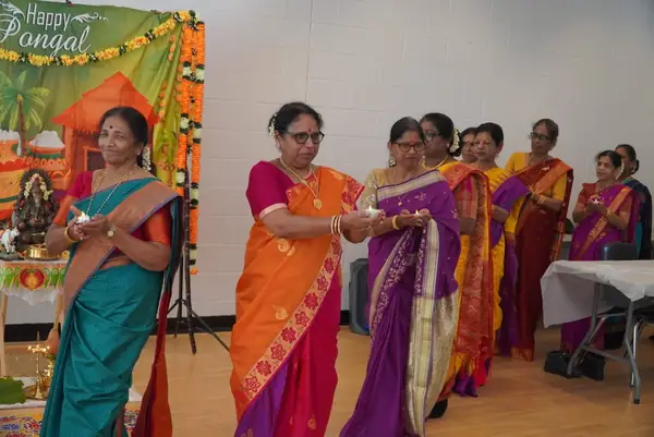 Women in colourful saris taking part in a ceremony indoors