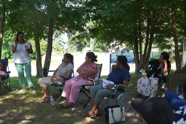 People seated in lawn chairs in a shaded park