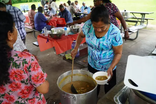 A woman serving food from a large pot at a picnic