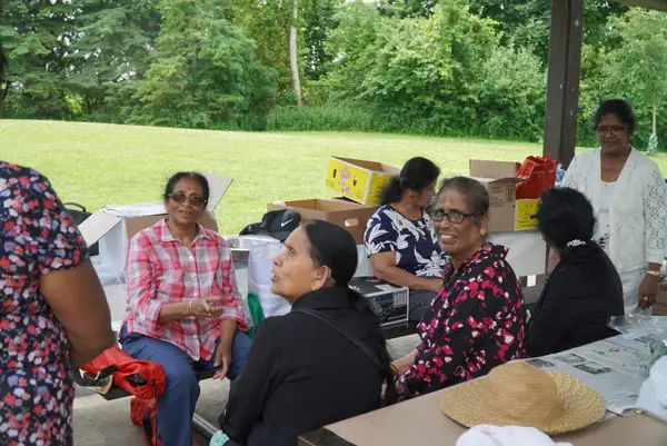 People seated together at a picnic table on the lawn