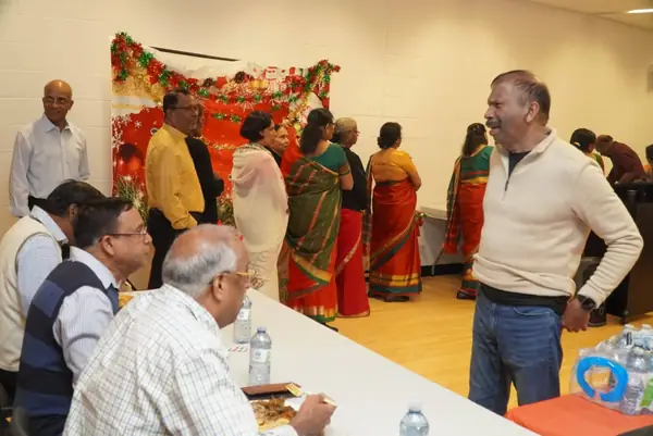 People gathered indoors near a decorated stage