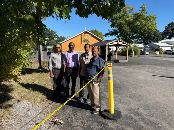 People standing in a parking area beside a wooden building