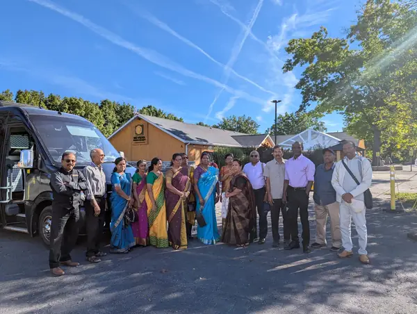 Group posing in front of a bus and a wooden building