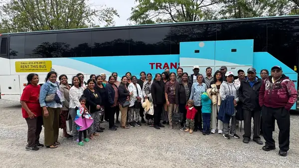Large group posing in front of a tour bus