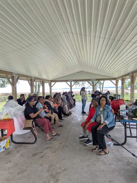 People seated at picnic tables under a pavilion