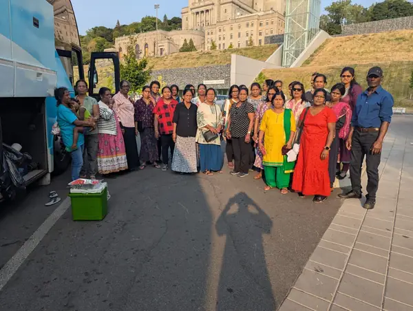 Large group posing on a paved area beside a bus