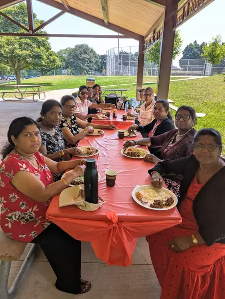 People seated at a long table with an orange tablecloth