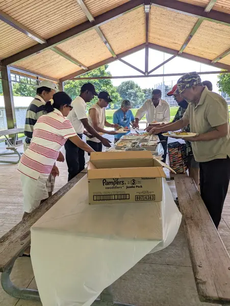 People serving food at a table under a pavilion