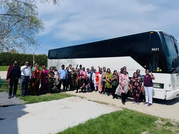 Large group posing beside a tour bus