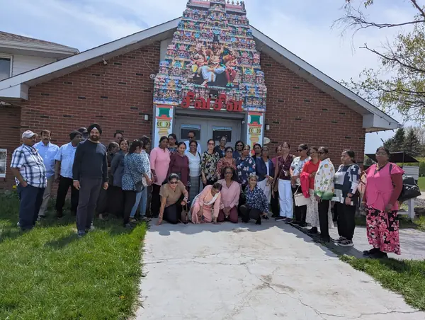 Large group posing in front of a brick building with a decorated gable