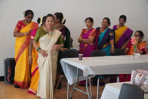 Women in saris standing at a table in a hall