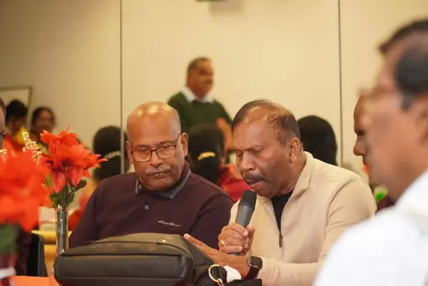A man speaking into a microphone while seated