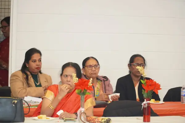People seated at a table with red flowers