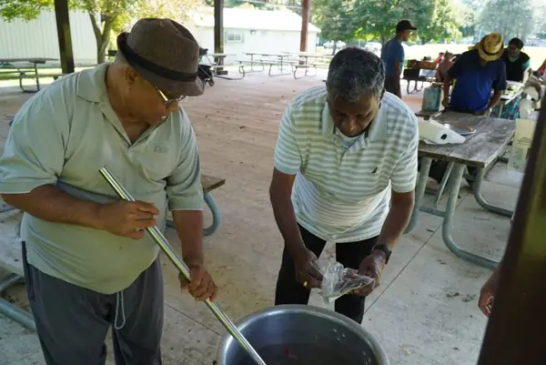 A man stirring a large pot outdoors