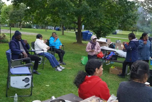 People seated at picnic tables in a park