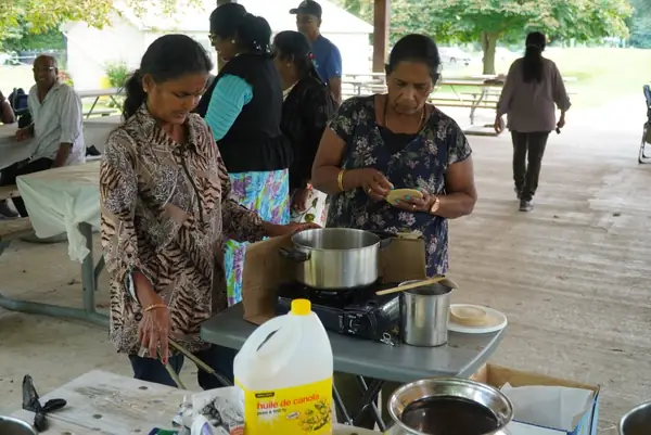 People cooking outdoors at a picnic table