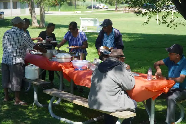 People seated at a picnic table with an orange tablecloth