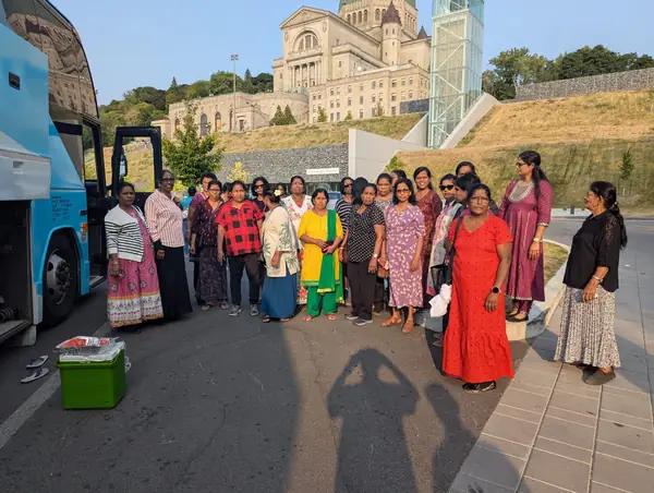 Large group posing near a bus in front of a large building