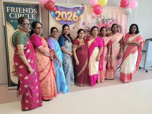 Women in saris posing in front of a 2026 backdrop with balloons