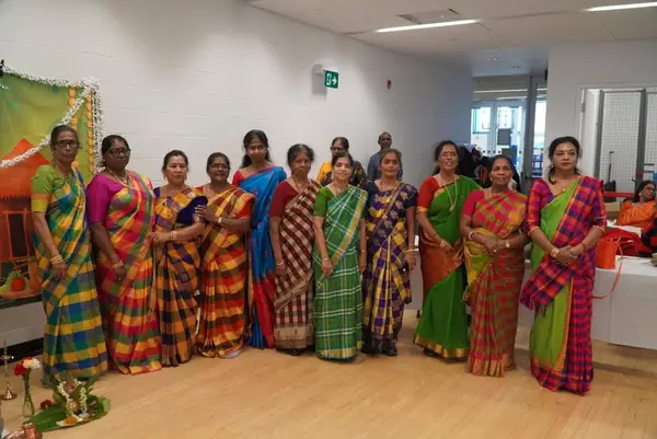Row of women in saris posing in a hall