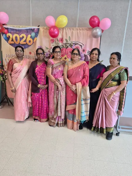 Women in saris posing in front of a 2026 backdrop with balloons
