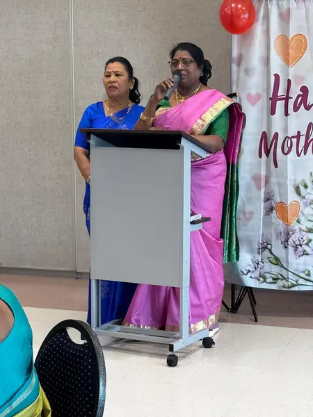 Two women at a podium beside a Mother's Day banner