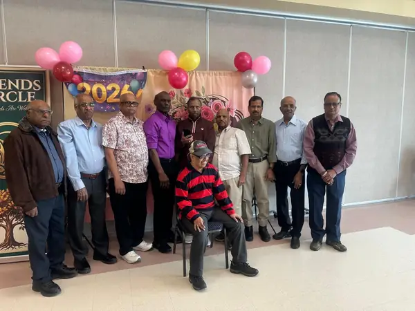Group of men posing in front of a backdrop with balloons